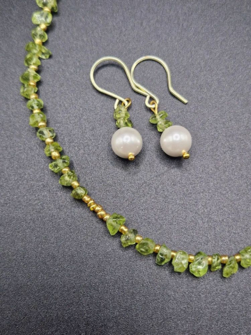 Setul este realizat din peridot, forme neregulate și cercei cu Perlă Mallorca. [3]