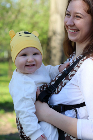 Marsupiu ergonomic Luna Una de culoare neagra, purtat de un părinte cu bebeluș. Design ajustabil, bretele moi și glugă pentru susținerea capului. [2]