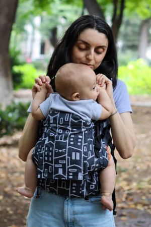Babywearing - Marsupiu ergonomic Luna Una de culoare neagra, purtat de un părinte cu bebeluș. Design ajustabil, bretele moi și glugă pentru susținerea capului.