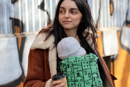 Marsupiu ergonomic Luna Una de culoare neagra, purtat de un părinte cu bebeluș. Design ajustabil, bretele moi și glugă pentru susținerea capului. [2]