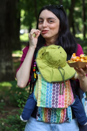 Luna UNA - Marsupiu ergonomic Luna Una de culoare neagra, purtat de un părinte cu bebeluș. Design ajustabil, bretele moi și glugă pentru susținerea capului.