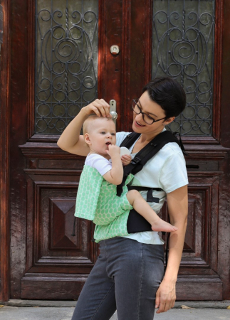 Marsupiu ergonomic Luna Una de culoare neagra, purtat de un părinte cu bebeluș. Design ajustabil, bretele moi și glugă pentru susținerea capului. [1]