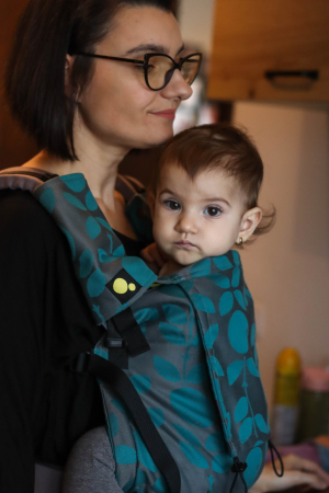 Luna UNA (0-36 Luni) - Marsupiu ergonomic Luna Una editie limitata, purtat de un părinte cu bebeluș. Design ajustabil, bretele moi și glugă pentru susținerea capului.