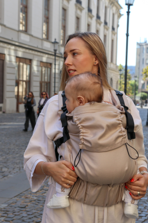 Luna UNA - Marsupiu ergonomic Luna Una de culoare neagra, purtat de un părinte cu bebeluș. Design ajustabil, bretele moi și glugă pentru susținerea capului.