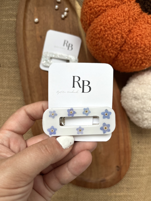 Agrafe de păr handmade din rășină, disponibile în maro cu sclipici, alb cu sclipici și alb cu flori „Nu mă uita”, inspirate de culorile cozy de toamnă. [1]