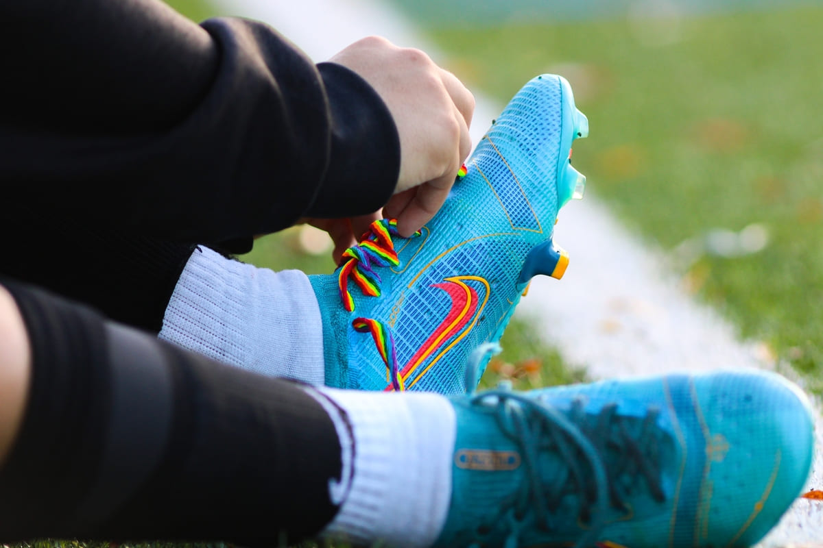 close up fotbalist pe iarba care leaga sireturile la ghete fotbal Nike turcoaz