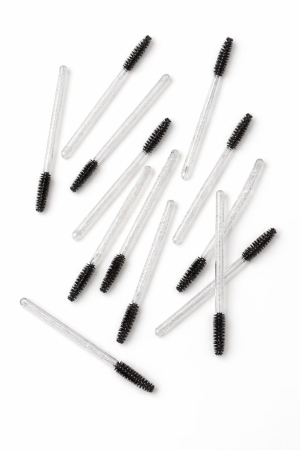 Consumabile - Set de periuțe colorate din silicon pentru gene, cu mâner negru și capăt flexibil în nuanțe de roz și mov, dispuse în evantai pe o suprafață albă.