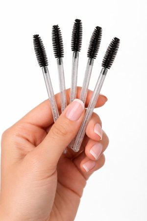 Set de periuțe colorate din silicon pentru gene, cu mâner negru și capăt flexibil în nuanțe de roz și mov, dispuse în evantai pe o suprafață albă. [1]