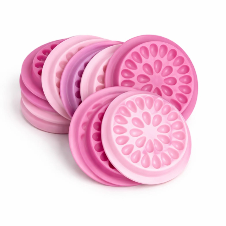 Consumabile - Suport din plastic roz în formă de floare cu multiple cavități circulare pentru adeziv și margini crestate, așezat pe o masă de lucru lângă o cutie de extensii de gene.
