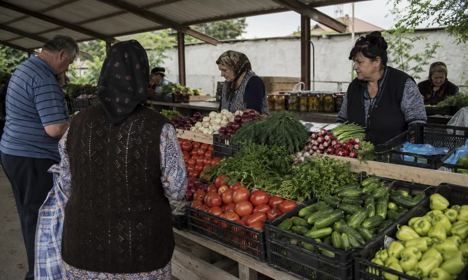 Piata de cartier romaneasca cu tarabe pline de rosii, castraveti, ceapa si ridichi