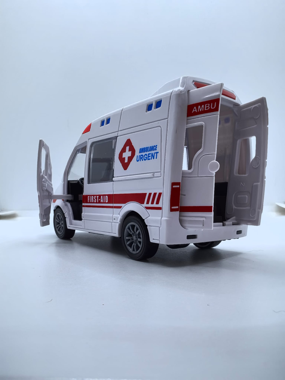 Mașinuță de jucărie ambulanță de culoare albă cu ușile din spate și portiera față deschise, inscripționată cu textul AMBULANCE URGENT. [4]