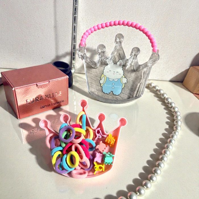 Cutie transparentă în formă de coroană cu mâner din mărgele roz, plină cu elastice și clame de păr colorate. [3]