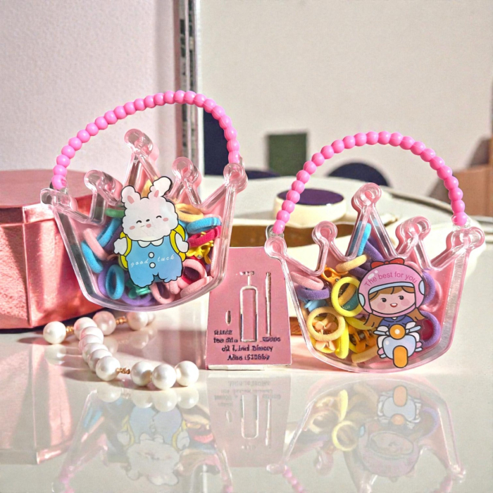 Cutie transparentă în formă de coroană cu mâner din mărgele roz, plină cu elastice și clame de păr colorate. [1]