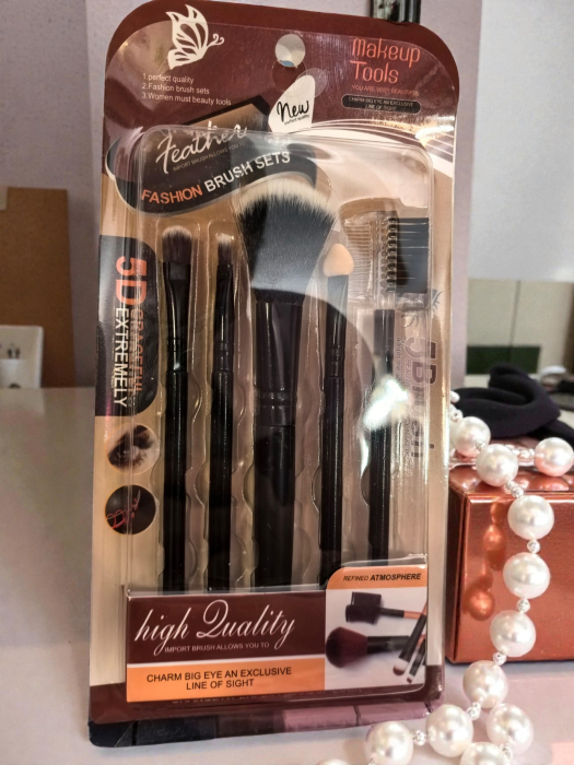 Set 5 pensule de machiaj negre cu ferule aurii, așezate ordonat pe un fundal neutru. [2]