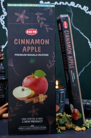 Accesorii pentru Casă - Cutie neagră elegantă de bețișoare parfumate HEM Premium Masala cu măr și scorțișoară lângă o lumânare aprinsă.