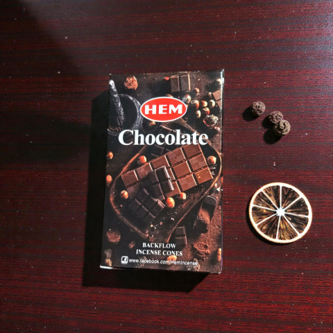 Conuri Parfumate Backflow - Cutie de conuri parfumate HEM BackFlow cu aroma de ciocolată și elemente decorative de citrice pe fundal de lemn.