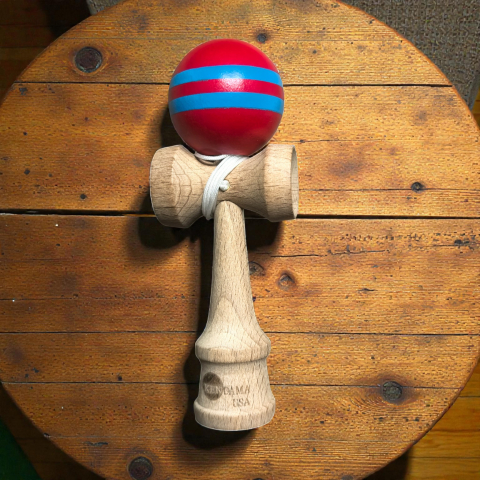Kendama mini de 12 cm din lemn natural cu bilă lucioasă dungată în culori galben și negru.