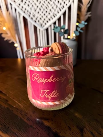 Delicii Parfumate: Lumânări Desert - Lumânare artizanală stratificată în pahar de sticlă, design Raspberry Trifle cu ceară roșie și maro, decorată la suprafață cu zmeură și macarons din ceară.