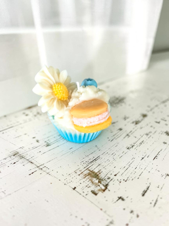 Delicii Parfumate: Lumânări Desert - O colecție amplă de lumânări artizanale tip cupcake, în diverse culori vibrante, decorate cu flori margarete, fructe de pădure și macarons din ceară.