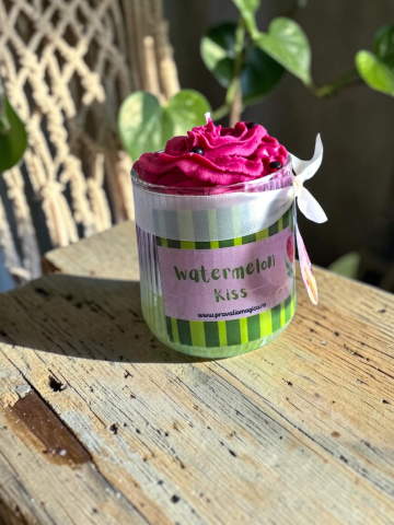 Delicii Parfumate: Lumânări Desert - Lumânare din ceară de soia în pahar de sticlă, cu etichetă Prăvălia Magică, având un top voluminos din ceară roz modelată sub formă de frișcă, cu mici semințe negre, inspirată de pepenele roșu.