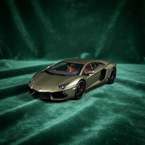Mașini de colecție - Machetă auto metalică Lamborghini Revuelto la scara 1:24, de culoare auriu mat, expusă pe un fundal din catifea verde