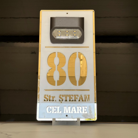 Plăcuță adresă casă albă cu detalii aurii și lumină solară – număr stradal personalizat, vizibil pe timp de noapte. [1]